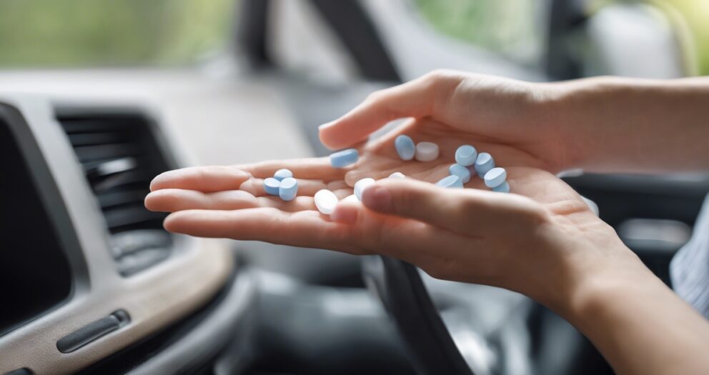 Handen houden verschillende blauwe en witte pillen vast in een auto, met het interieur zichtbaar op de achtergrond.