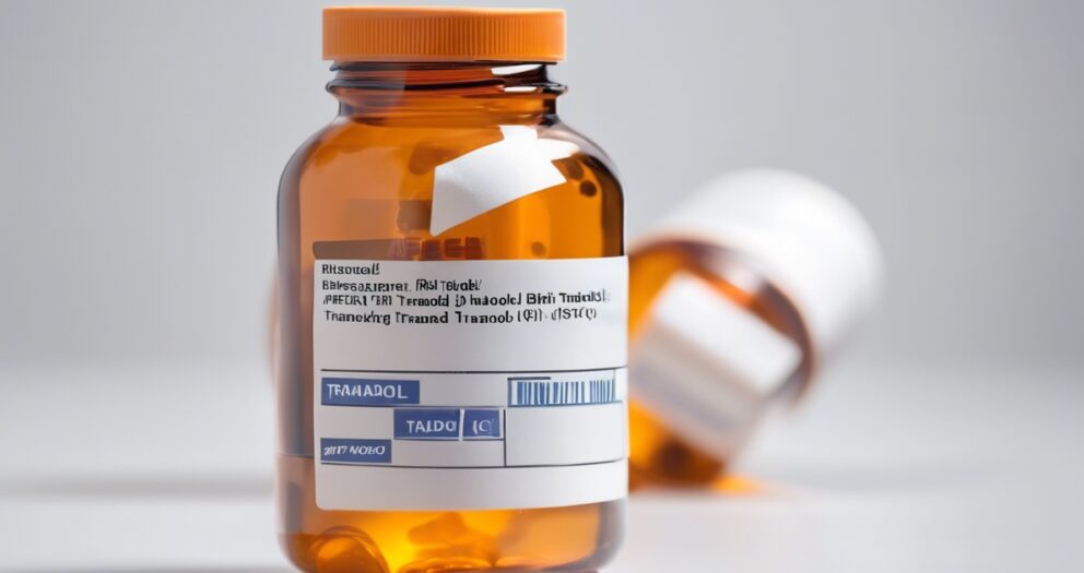 Een close-upfoto van een oranje flesje met voorgeschreven pillen met het label "Tramadol" in focus, terwijl een ander vergelijkbaar flesje wazig op de achtergrond ligt. De labeltekst is zichtbaar maar niet volledig leesbaar.